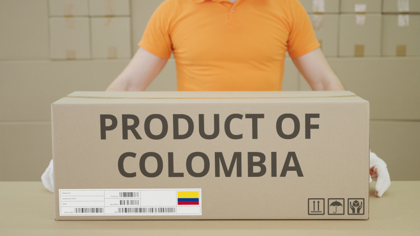 Hombre sosteniendo una caja que dice “product of Colombia” que tiene bienes colombianos.